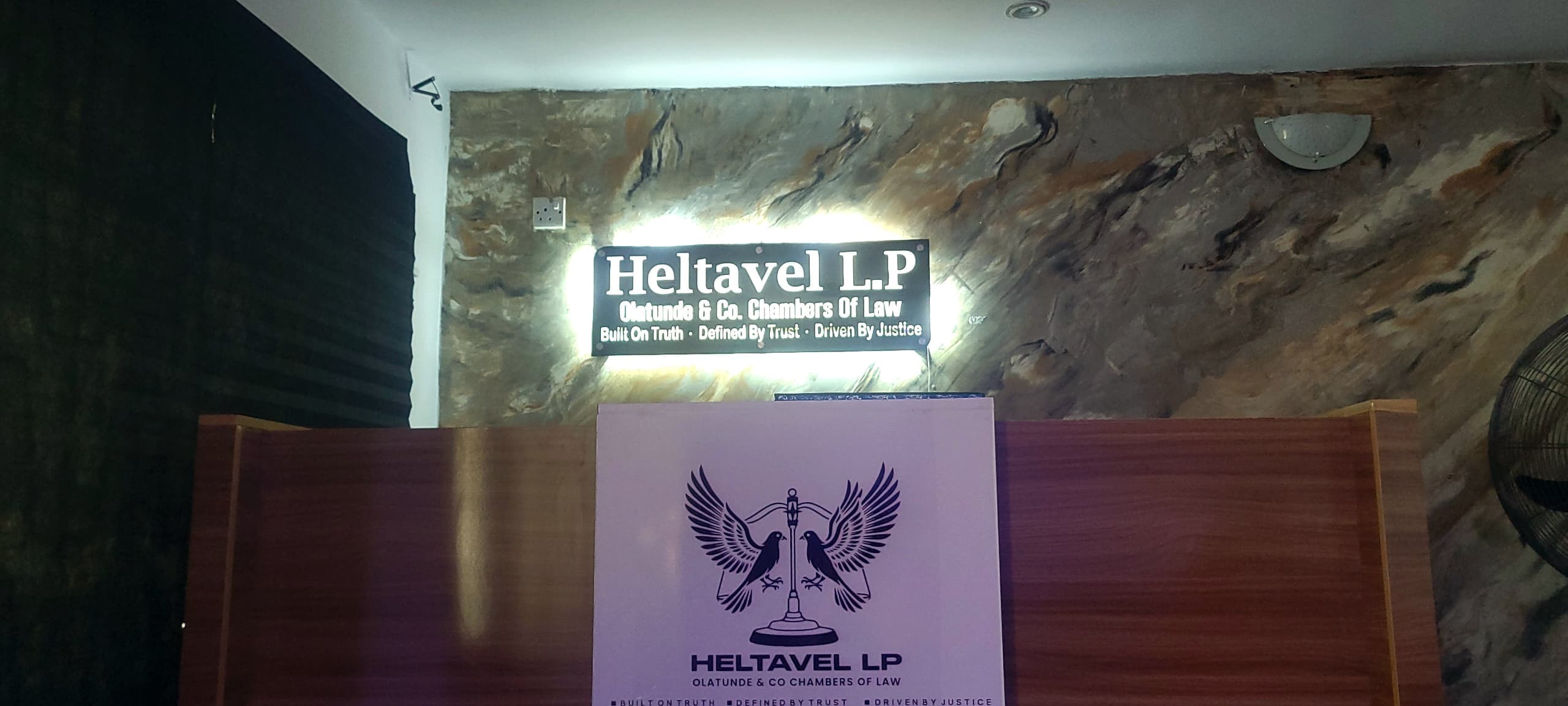 Heltavel Legal reception showing illuminated office signage and the firm's branding